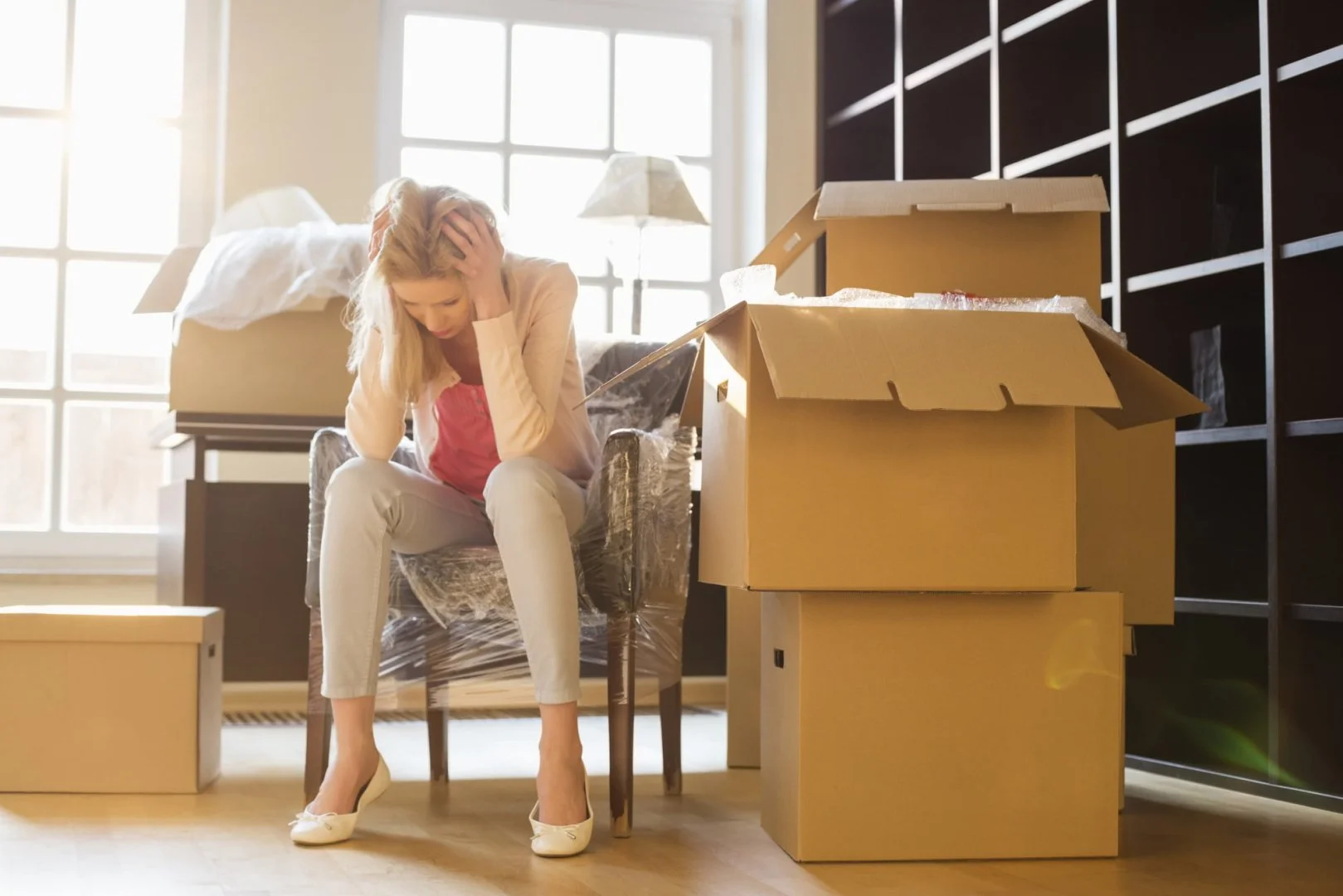 Making Moving Less Stressful Stressed woman surrounded by moving boxes in a sunlit room.
