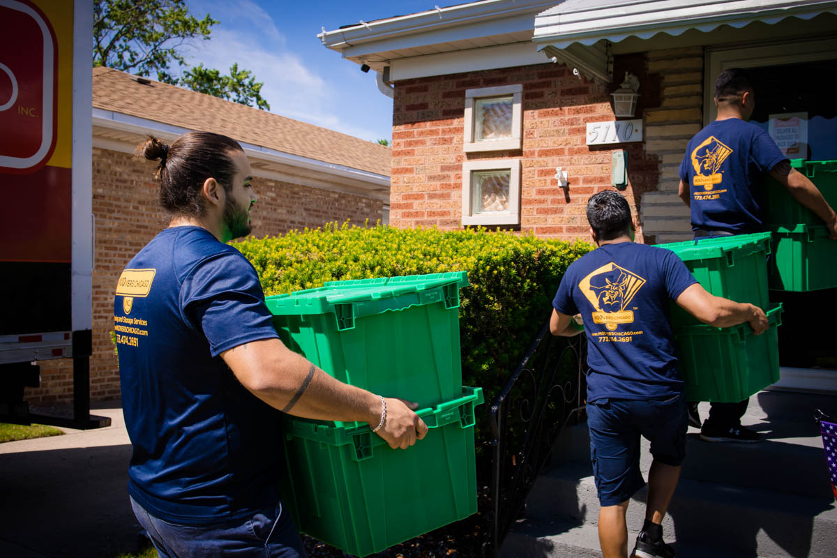Local movers carrying green boxes into a house in Chicago.