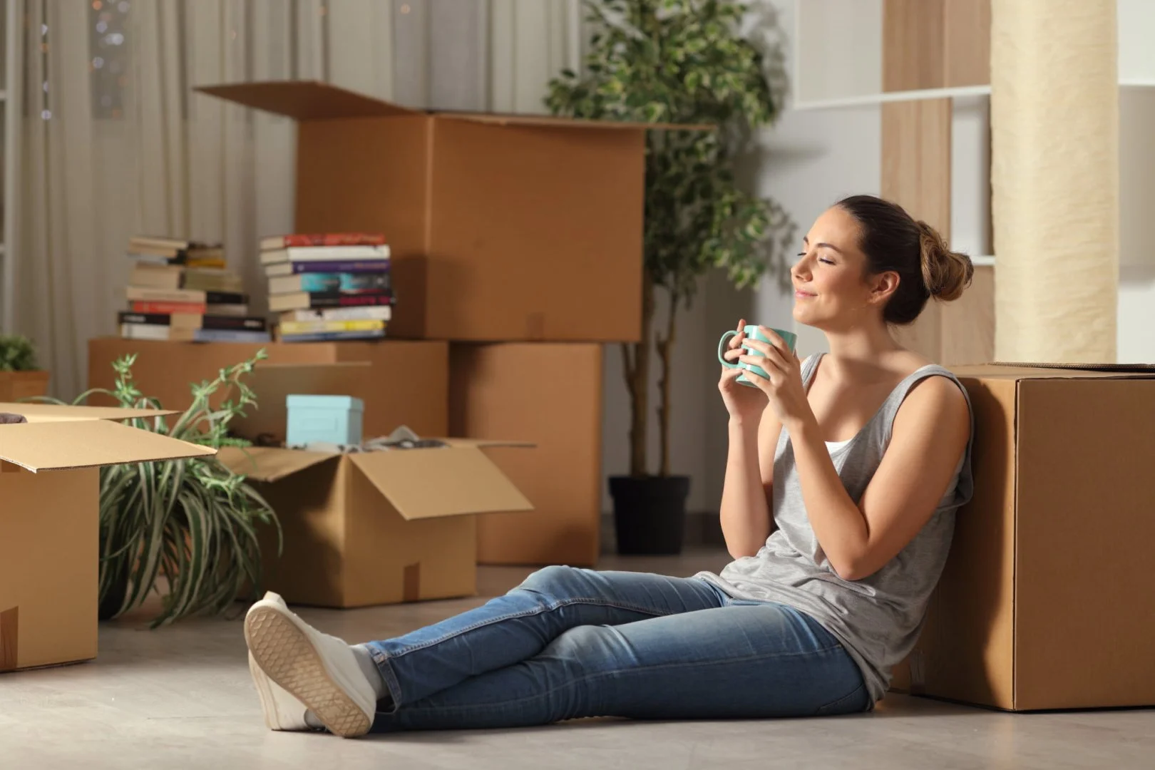 Relaxing During a Move with Moovers Chicago Woman relaxing with coffee among moving boxes, Moovers Chicago.