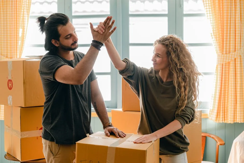 Packing Tips for a Smooth Move Two people high-fiving while packing boxes for a move.
