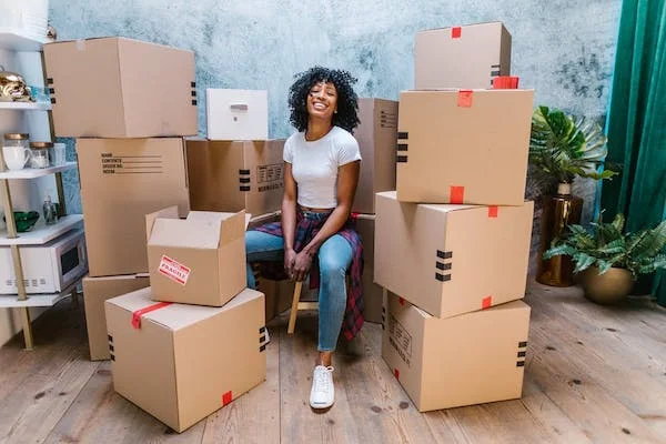 Efficient Moving Services by Moovers Chicago Smiling woman surrounded by moving boxes, representing local and long-distance moving services.