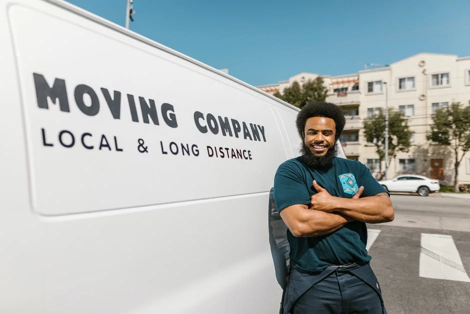 Professional Moving Services in Chicago Smiling mover standing by a moving company van offering local and long distance services.