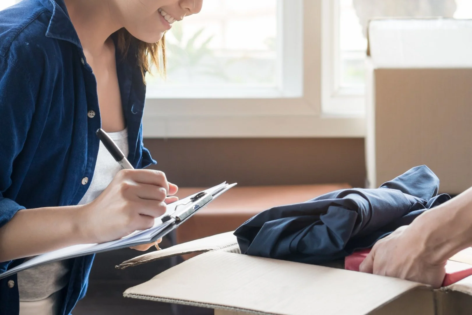Packing for a Move with Moovers Chicago Person packing clothes in a box, preparing for a move with Moovers Chicago.