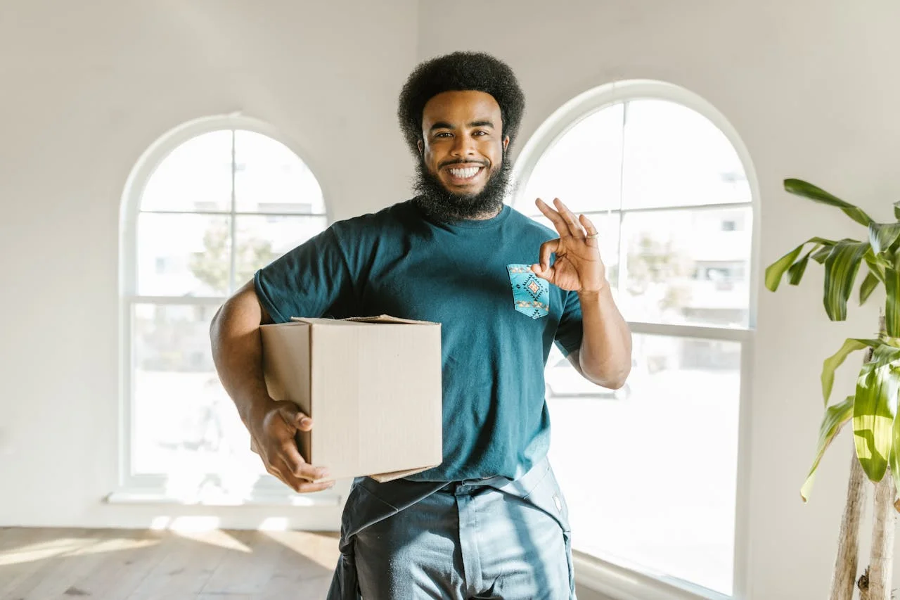 Friendly Mover from Moovers Chicago Smiling mover holding a box in a sunlit room, representing Moovers Chicago.