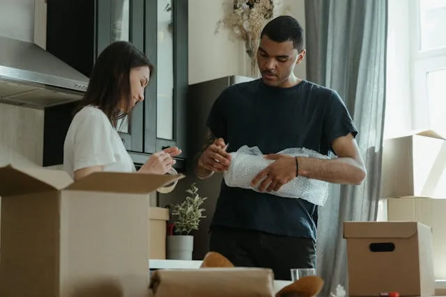 Two people wrapping items in bubble wrap