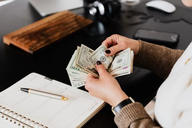 Person counting money at desk, planning moving services.