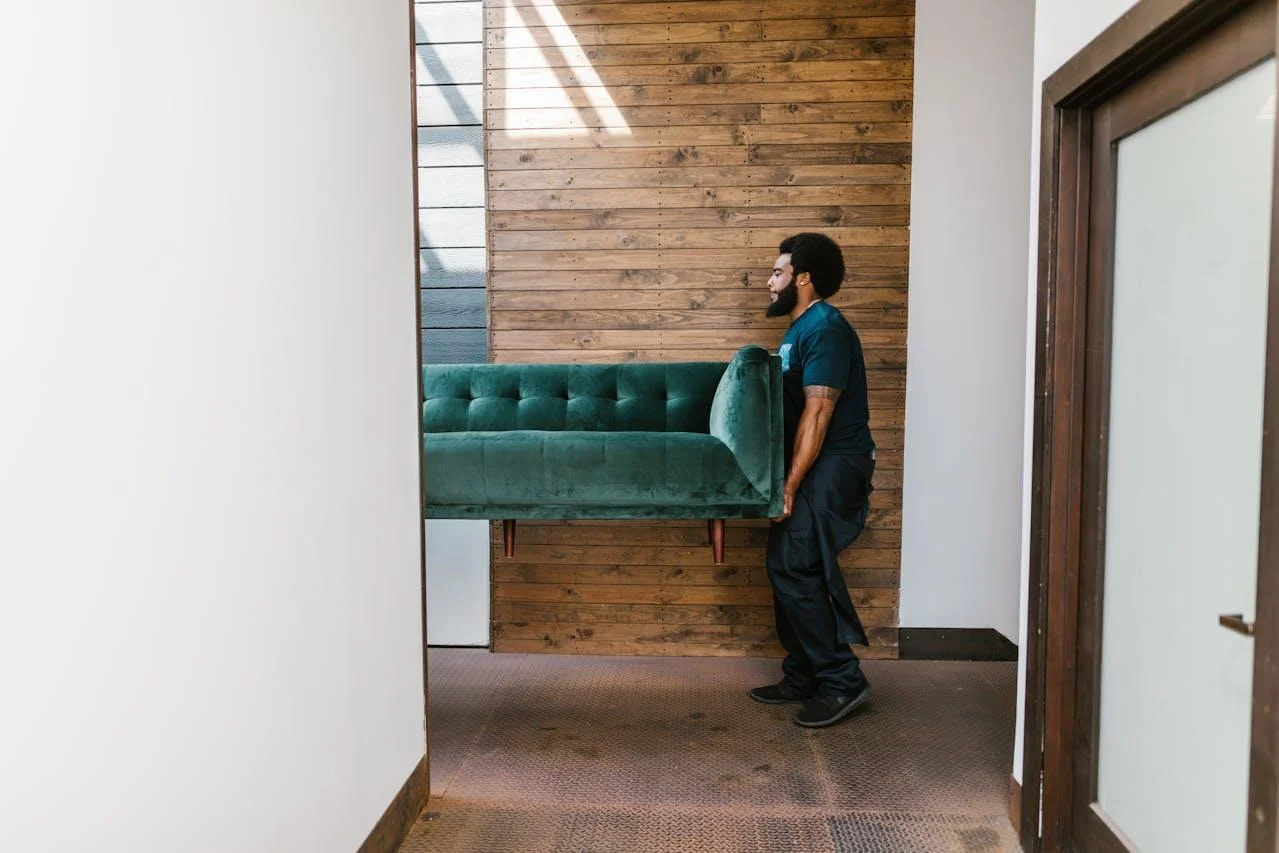 Professional Moving Services by Moovers Chicago Mover carrying a green couch in a hallway, Moovers Chicago.