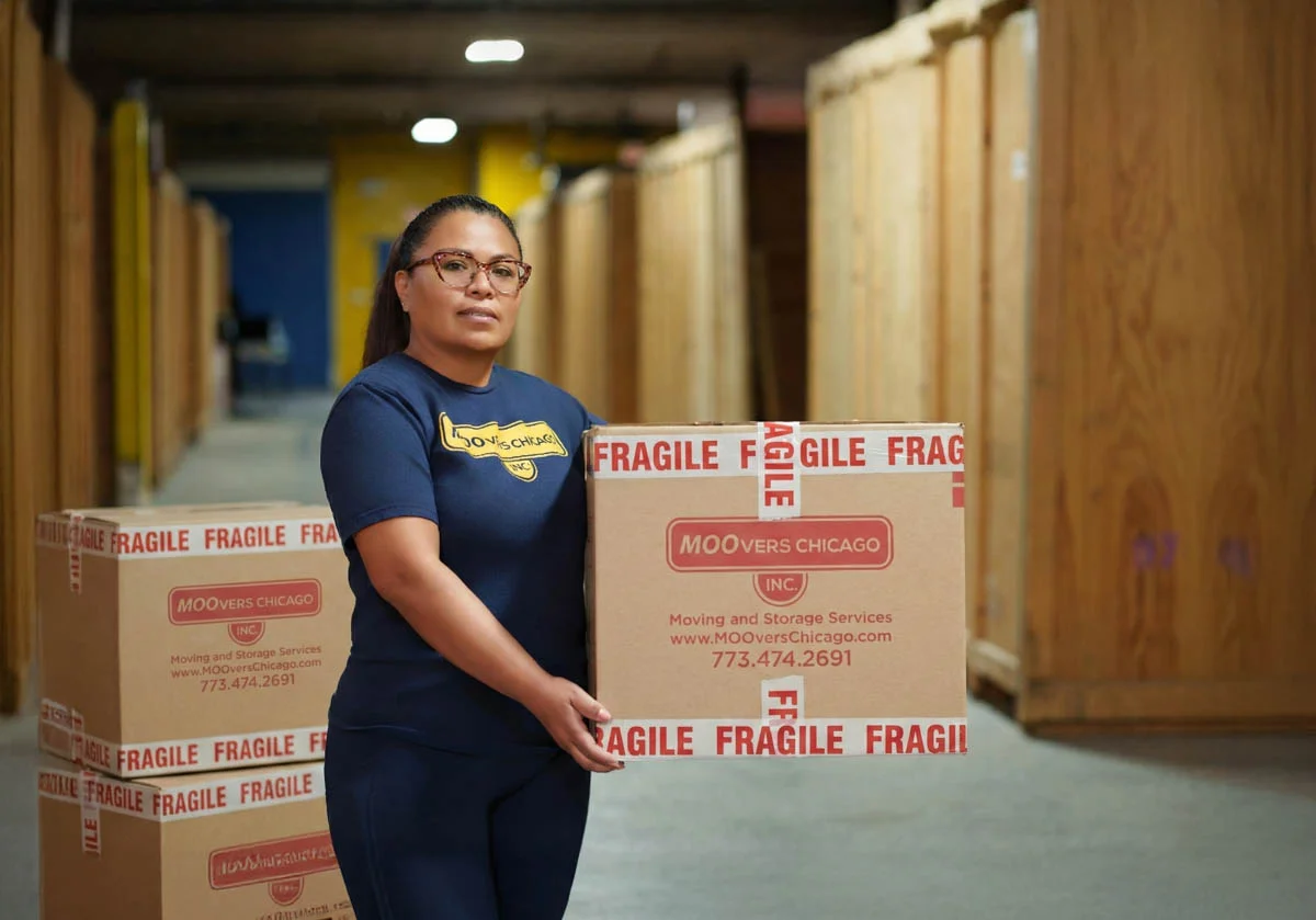 Moovers Chicago employee handling fragile boxes in storage facility.