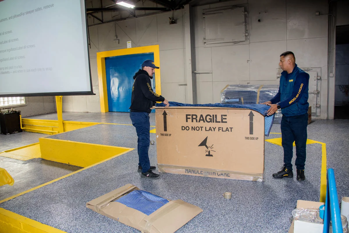 Movers handling a large fragile box at Moovers Chicago, a trusted moving company.