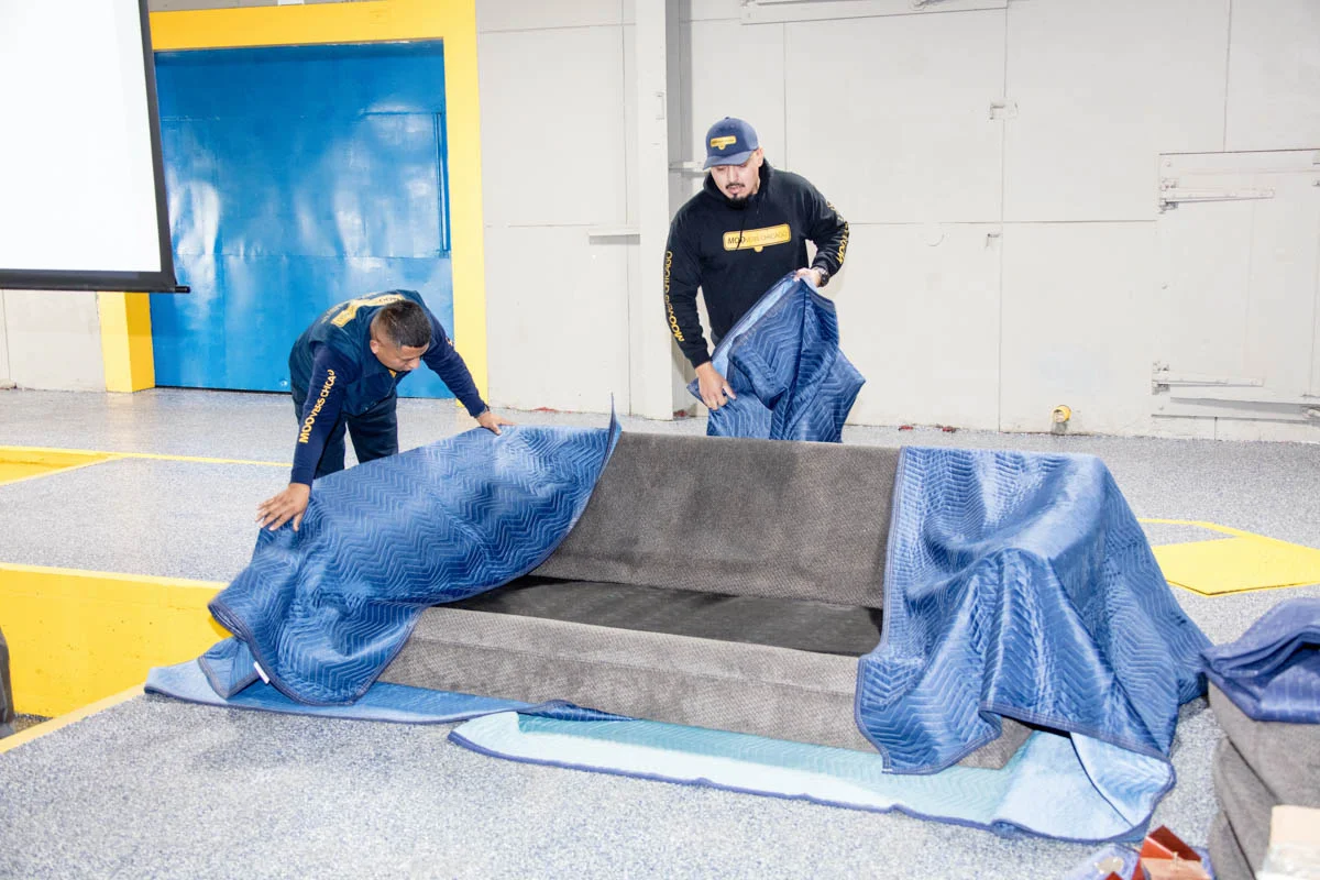 Professional movers wrapping a sofa for transport in Chicago.