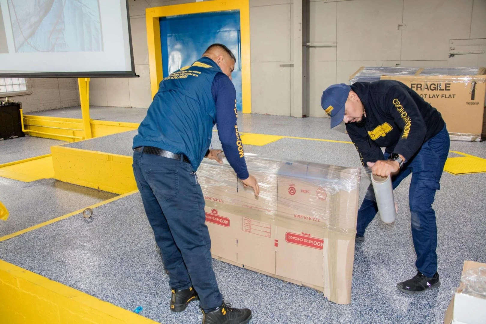 Professional movers packing a box in a warehouse, Moovers Chicago.