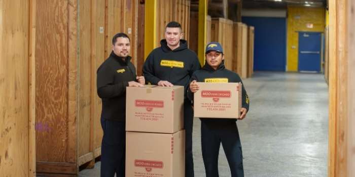 Moovers Chicago employee holding a moving box in a storage facility.